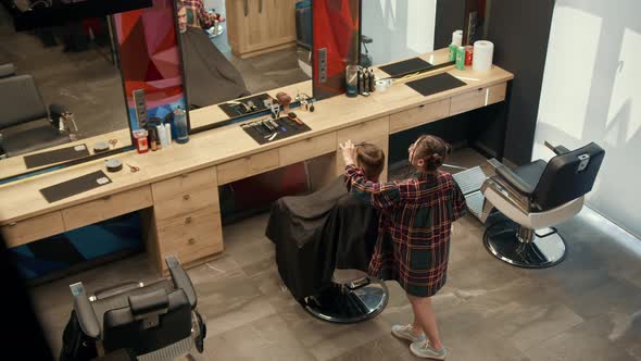 Barbershop: a woman barber cuts a client's man's hair