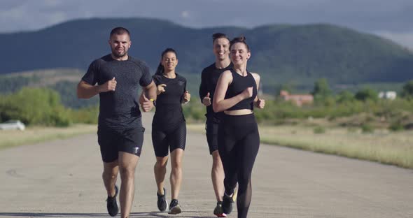 Multiethnic Group of Athletes Running Together on a Panoramic Countryside Road