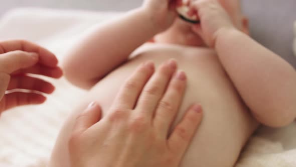 Mother Massaging Baby Tummy. Baby Skin Care and Development