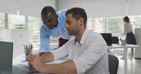 Diverse Business Colleagues Using Laptop Talking in Office