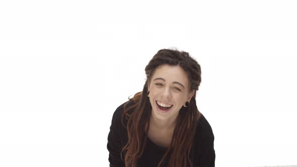 Attractive Caucasian Woman with Dreadlocks and Ear Tunnels Starting to Laugh From Something Funny