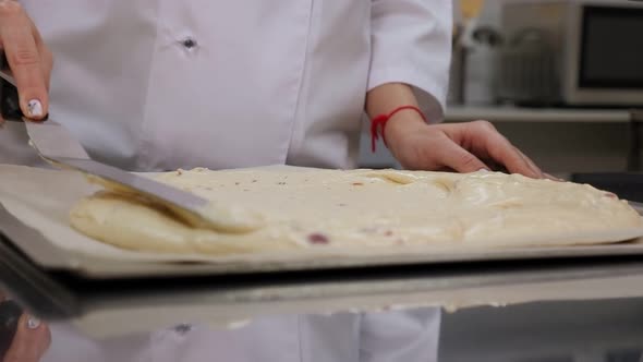 Closeup of the Pastry Chef Spreading the Dough in Baking Dish with a Spatula