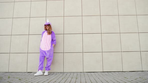 Funny cheerful happy young woman dancing outdoors on yellow wall.