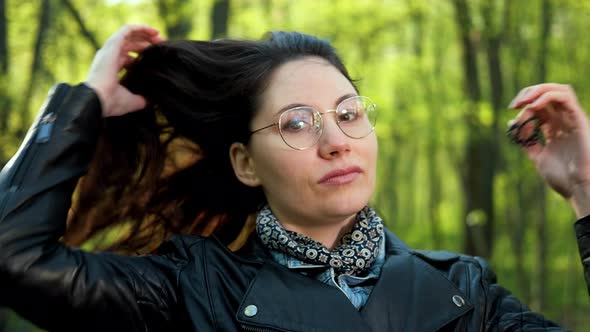 Woman with Glasses is Letting Down Her Lush Hair in the Park