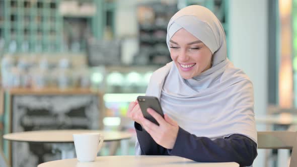 Excited Young Arab Woman Celebrating Success on Smartphone 