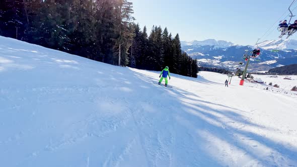 Boy on Snowboard in Motion Ride Downhill with Under Ski Lift