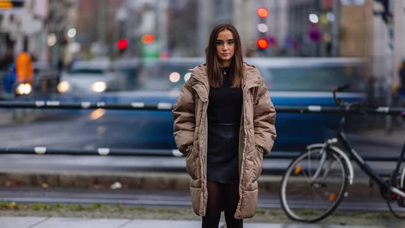 Time lapse of young woman standing in city street on autumn day looking at camera alone