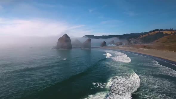 AERIAL: Drone shot flying towards large rock formations within Oregon's Pacific ocean.