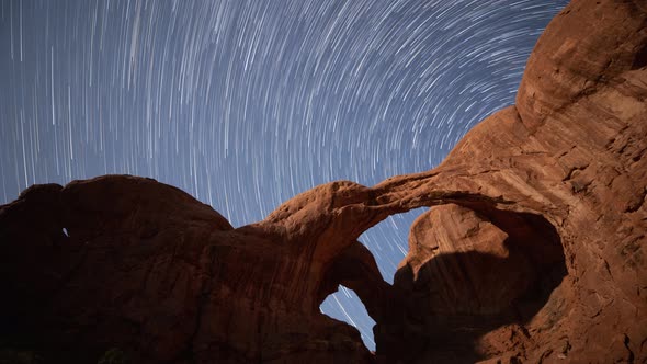 Time lapse of the night sky behind Double Arch in Arches National Park