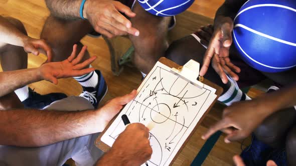 Upward view of coach assisting players on clipboard clipboard