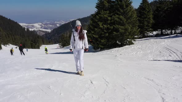 Young woman walking on ski track at the snowy mountain