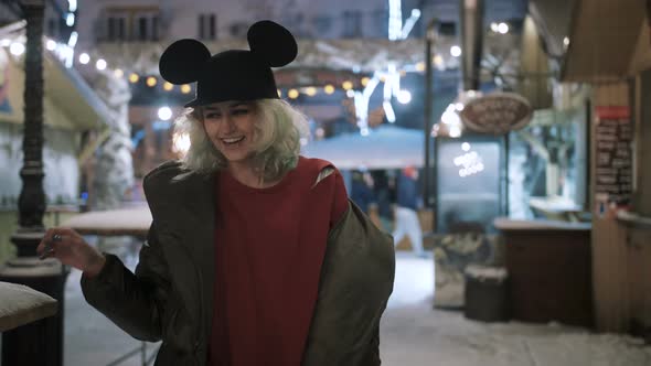 Young Funky Woman Outdoor in Wintertime at Night Having Fun with Snow