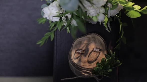 Beautiful Wedding Rings Lie on Wooden Stand with Wedding Bride's Bouquet