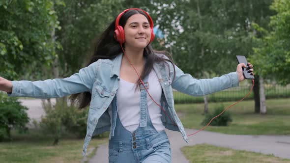 Cheerful Girl in Red Headphones Jumps and Listens To Music