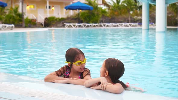 Adorable Little Girls Playing in Outdoor Swimming Pool Together