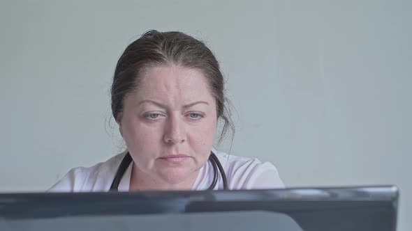 Portrait of a Middleaged Woman a Doctor Working on a Computer