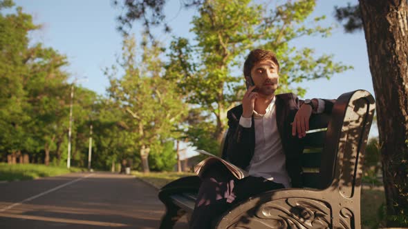 Slow Motion of Handsome Business Man Entrepreneur Man in Suit Sit on Bench in Green Park in the