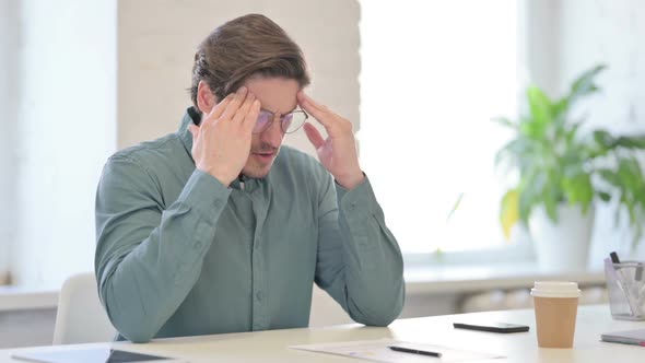 Middle Aged Man Sitting in Office with Headache