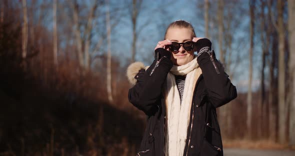 Happy Woman Putting on Sunglasses in Autumn