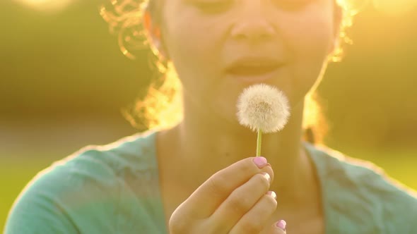 Beautiful Girl Blowing on a Dandelion Fluff Slowly Flies Through the Air