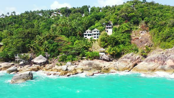 Luxury hotels and resorts on the rocky coast of thailand island with palm forest. aerial