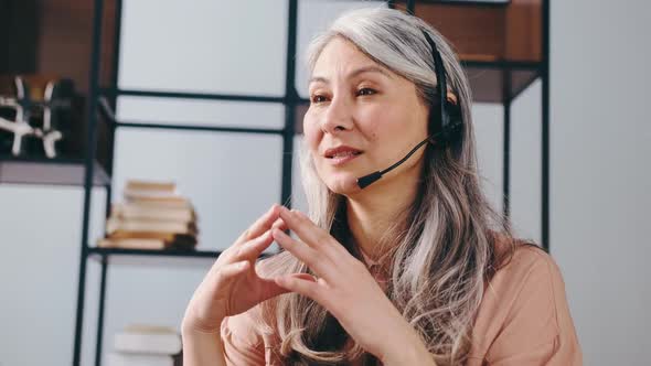 Happy Mature Businesswoman in Headset Speaking By Conference Call Looking at Computer Female Call