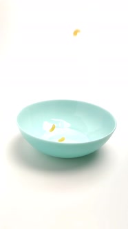 Wheat Pasta Falls on a Blue Plate on a White Background. Close-up, Slow-motion