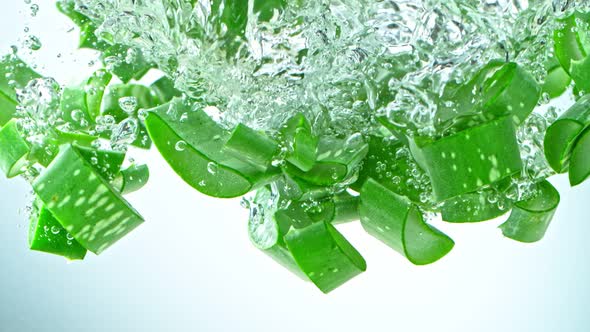 Super Slow Motion Shot of Aloe Vera Cuts Falling Into Water on White Background at 1000Fps.