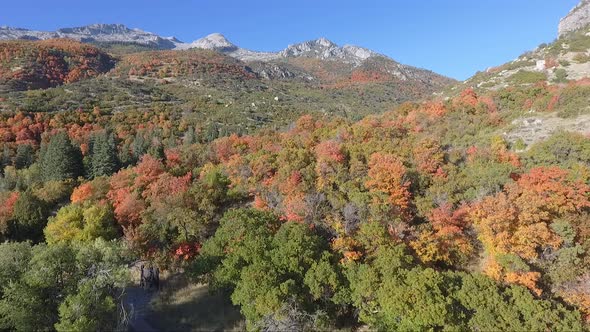 A drone flies past the rocks and slopes of  Dry Creek Trailhead in Alpine, Utah as leaves change int