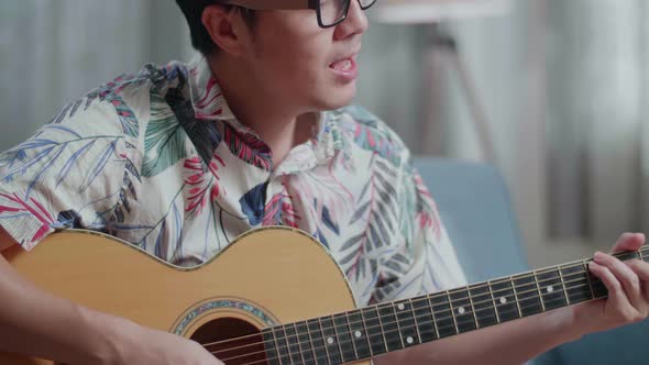 Close Up Of Asian Man Composer With Notebook On Table Singing And Playing Guitar At Home