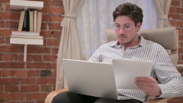 Middle Aged Man with Laptop Working on Documents on Sofa