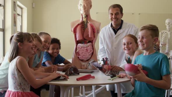 Male teacher and group of kids smiling in human anatomy class