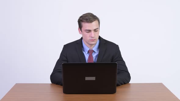 Young Happy Handsome Businessman Greeting Against Wooden Table