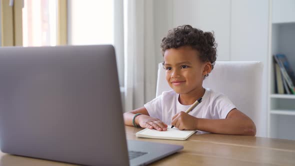 Cute Little African American Boy Having Online Class Using Laptop Doing Homework