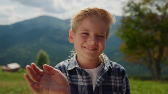 Smiling Boy Waving Hand on Green Meadow Close Up