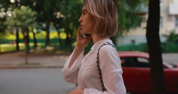 Woman Messaging By Mobile Phone Walking in a Summer City