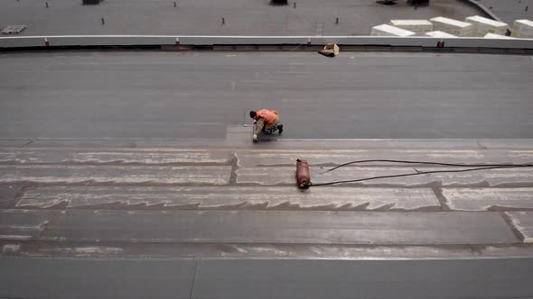 Workers at a Construction Site. The Process of Hydro Insulation of the Roof. With the Help of a