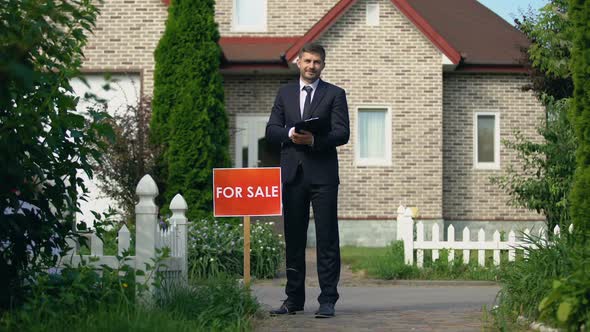 Smiling Real Estate Broker Holding Documents With Information for Clients, Sale