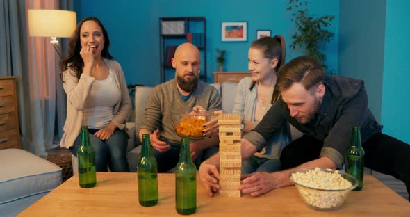 Friends on the Couch Drinking Beer Eating Snacks and Playing an Arcade Game Men Figuring