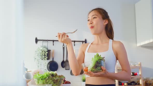 Asian attractive sport woman holding salad bowl and eat vegetables.