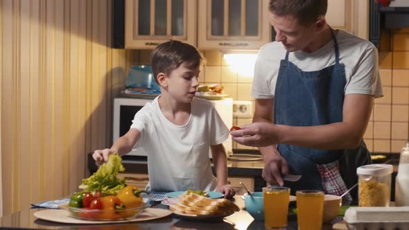 Caucasian father and son preparing vegetables to salad