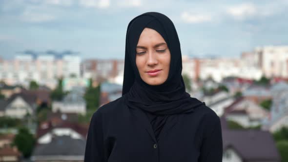 Portrait of Modern Muslim Young Woman in Black Hijab Posing Over Traditional Islamic City