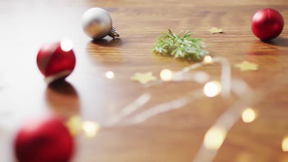 Video of christmas decorations with baubles and fir tree branches on wooden background