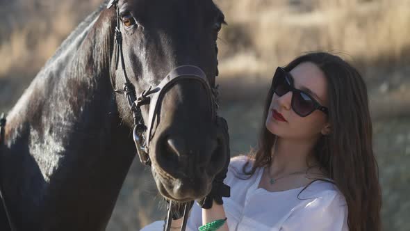 Slim Beautiful Caucasian Horsewoman in Sunglasses Caressing Animal Head in Slow Motion Standing