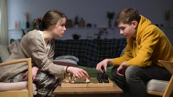 Young people learn to play chess at home in the evening