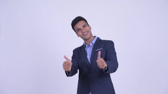 Happy Young Indian Businessman Pointing Up and Giving Thumbs Up