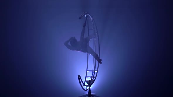 Graceful Gymnast Performs Tricks on a Special Design in a Dark Room. Blue Smoke Background. Slow
