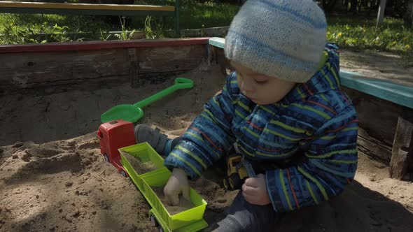 Toddler Kid Playing with Toy Car in Sandbox