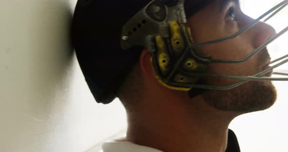 Cricket player sitting with his head leaning against wall in dressing room