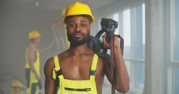 African Sexy Muscular Builder Posing Shirtless with Drill Slung Over His Shoulder